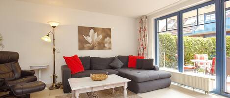 A living room with a sectional sofa, a coffee table, a floor lamp, and a large window with a view of the outdoors.