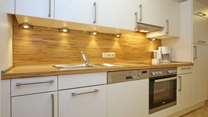 Una cocina moderna con armarios blancos, encimera de madera, lavavajillas integrado y horno.