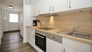 A modern kitchen with white cabinets, a stainless steel sink, and a Bosch oven. - Papillon Wohnung 05-6 (Ostseebad Boltenhagen)
