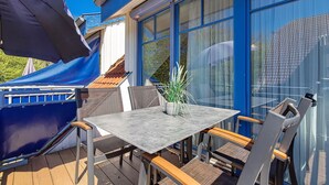 A patio with a table and chairs, a potted plant, and a blue awning. - Papillon Wohnung 05-6 (Ostseebad Boltenhagen)