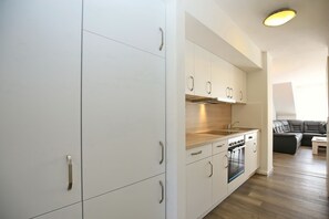 Eine moderne Küche mit weißen Schränken, Edelstahlgriffen und einem eingebauten Backofen.