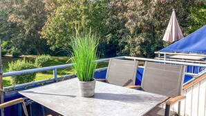 An outdoor patio with a table and chairs, a potted plant, and a blue canopy.