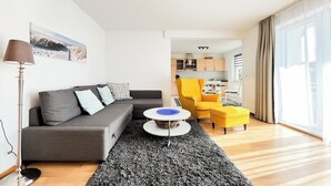 A modern living room with a grey sofa, a yellow armchair, and a round coffee table. - Waterkant - Muschel Wohnung 1 (Ostseebad Boltenhagen)