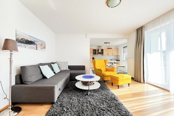 Un salon moderne avec un canapé gris, un fauteuil jaune et une table basse ronde.