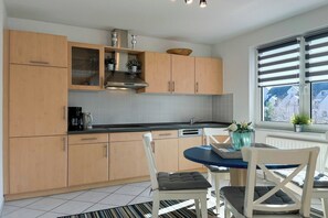 Une cuisine moderne avec des meubles en bois, une cuisinière à gaz et un coin repas comprenant une table et des chaises.