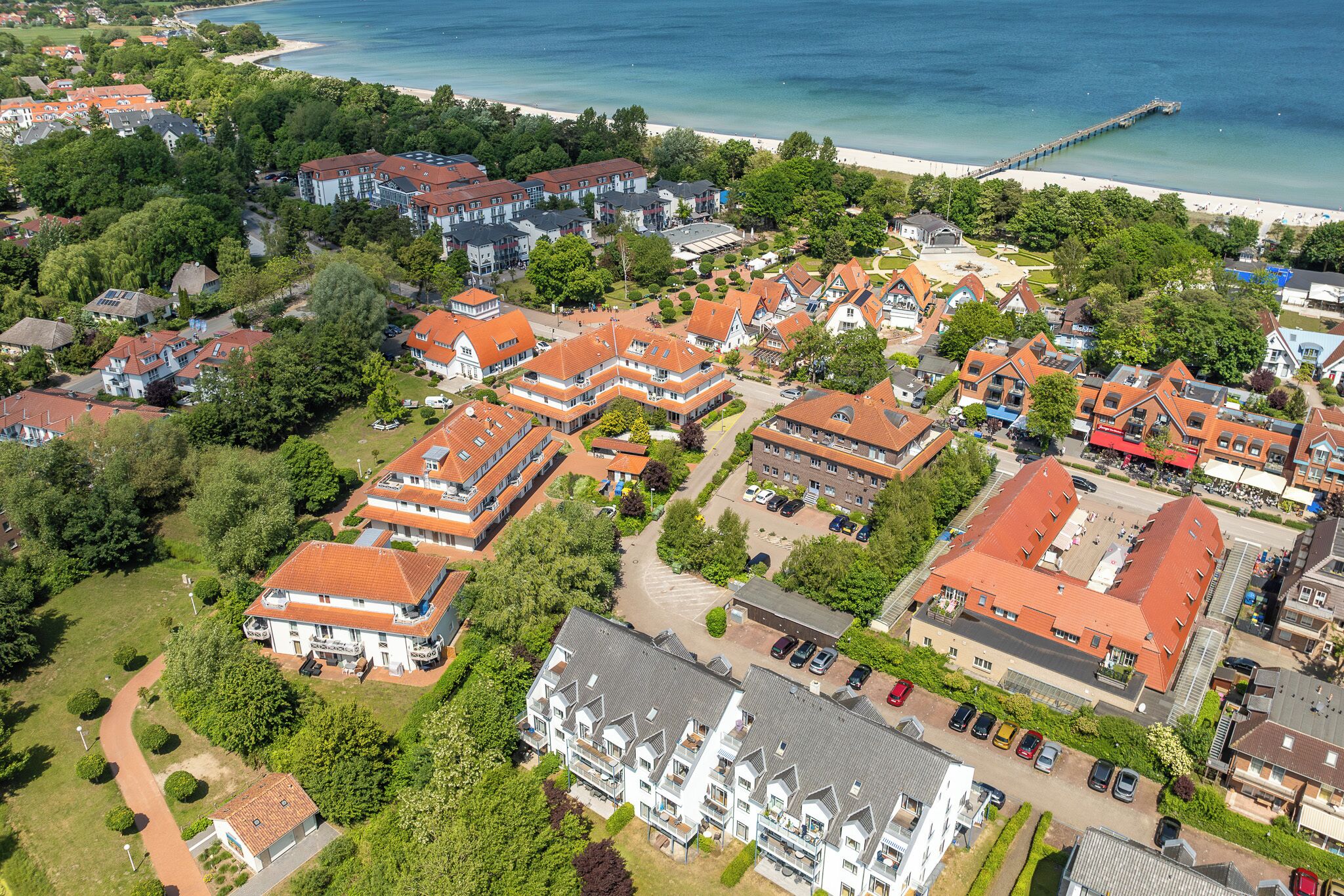 Vista aérea de uma área residencial com vários edifícios, uma praia e um cais.