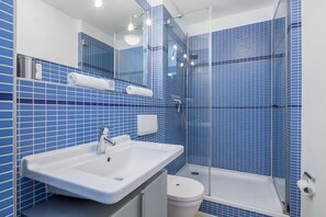 Ein Badezimmer mit einem weißen Waschbecken, einer Toilette und einer Duschkabine.