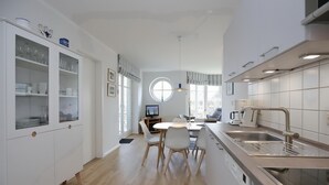 Une cuisine moderne avec des meubles blancs, une table de salle à manger ronde entourée de chaises et un four encastré.