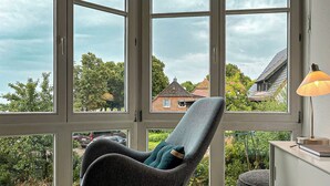 Une pièce avec une grande fenêtre, un fauteuil à bascule et une lampe.