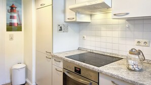 A modern kitchen with white cabinets, a built-in stove, and a tiled backsplash.