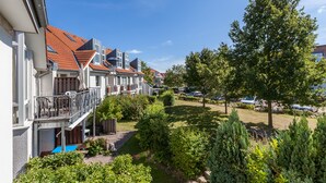 A row of townhouses with balconies, a swimming pool, and well-maintained gardens.