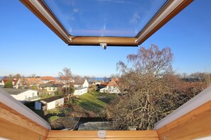 A skylight window with a clear view of a residential area, including houses and trees. - Fritz-reuter-weg 2 Wohnung 11 (Ostseebad Boltenhagen)