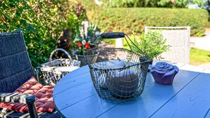 A round table with a blue tablecloth, a wicker basket with a plant, and a purple flower pot. - Einliegerwohnung Arielle 1 (Boltenhagen/Redewisch)