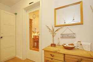 Une pièce avec une commode en bois, un miroir et une pancarte de bienvenue.