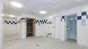 Ein sauberes, gefliesstes Badezimmer mit Duschbereich, einer Toilette und einer Tür mit Glasfenster.