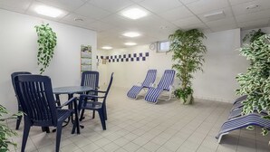 Ein Zimmer mit Esstisch und Stühlen, Lounge-Möbeln und Blumentöpfen.