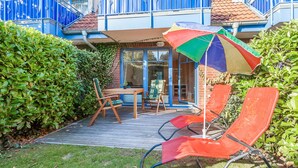 Um pátio com deck de madeira, móveis de exterior e um guarda-sol colorido.