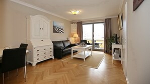 Ein Wohnzimmer mit einem weißen Schrank, einer schwarzen Couch und einem Couchtisch.