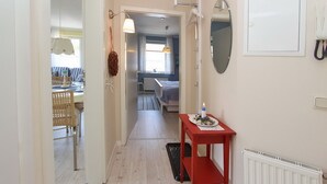 Ein Flur mit einem roten Tisch, einem Heizkörper und einem Spiegel an der Wand.