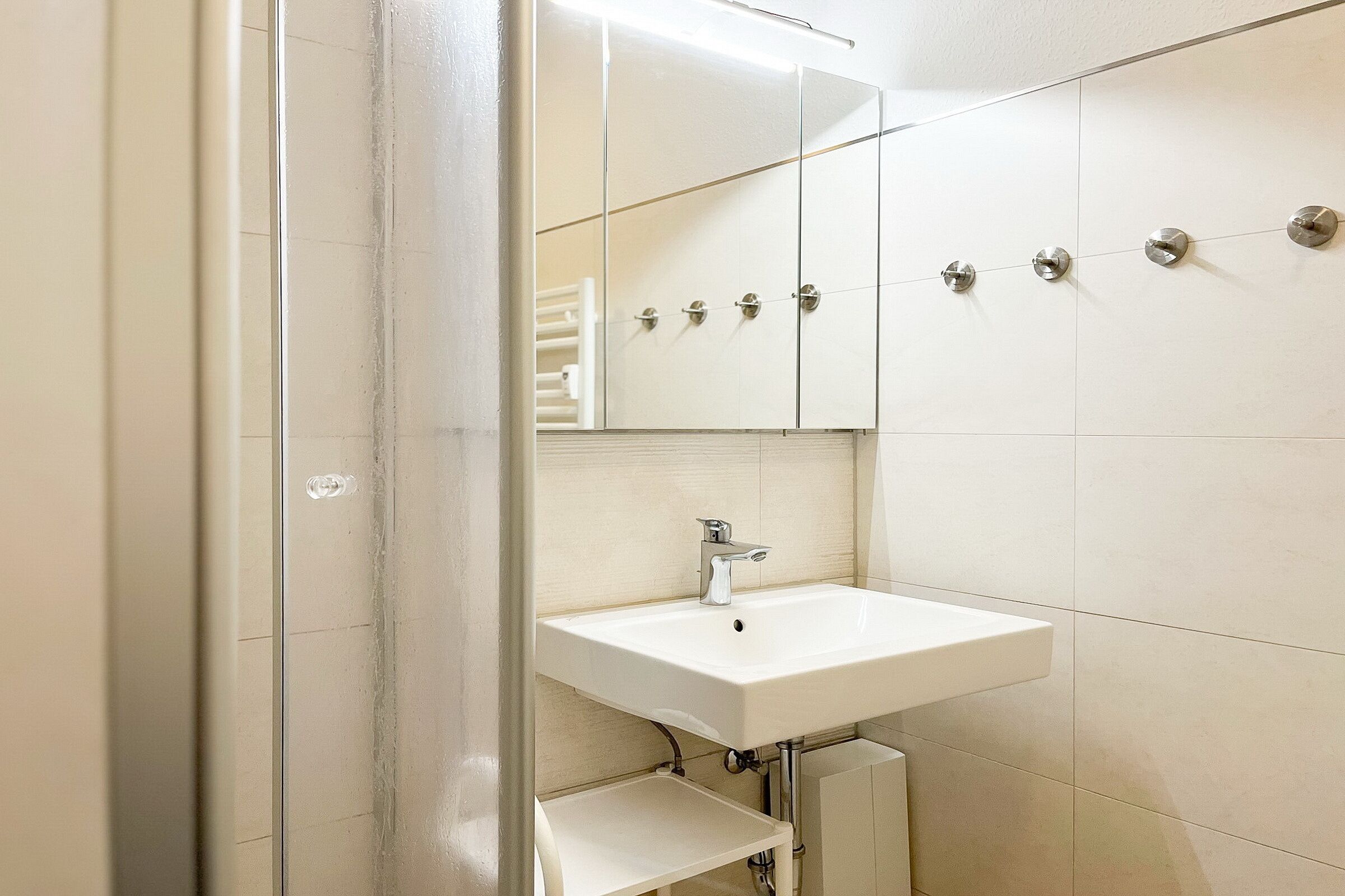Une salle de bain avec un lavabo blanc, un miroir et des armoires.