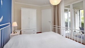 Une chambre à coucher avec un grand lit, une armoire, une table de chevet avec une lampe et un balcon avec une chaise.