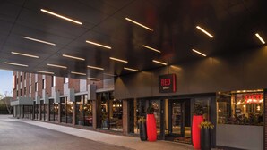 A modern hotel exterior with a prominent 'RED' sign, large potted plants, and a clean, well-lit facade. - Radisson RED London Gatwick Airport (Crawley)