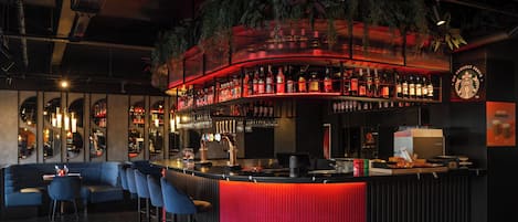 A bar area with a curved counter, bar stools, and a red accent wall.