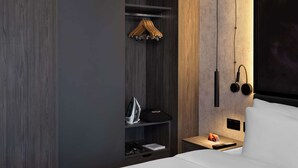 A modern hotel room with a wardrobe, a bedside table with a lamp, and a bed. - Radisson RED London Gatwick Airport (Crawley)