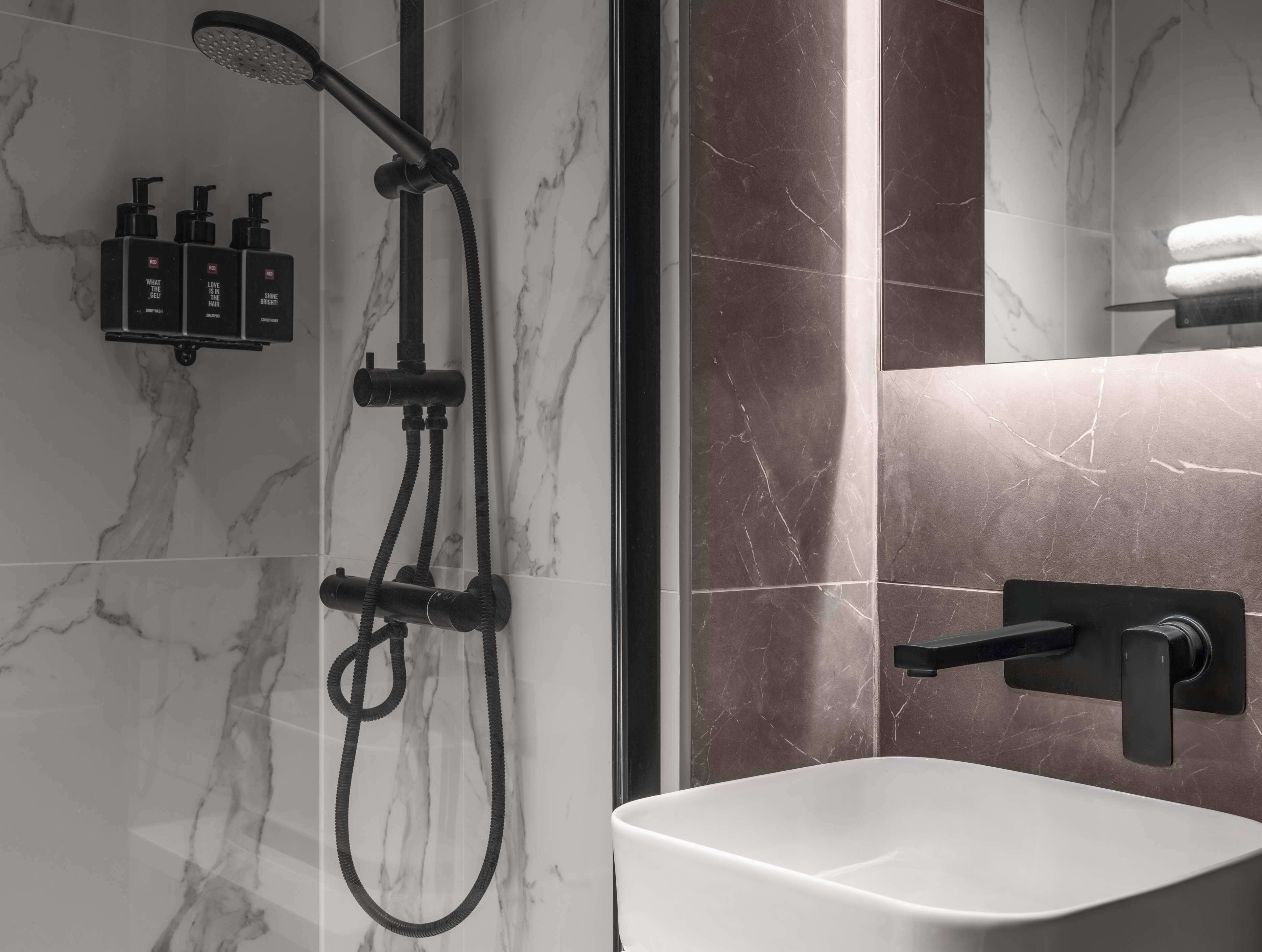 Een moderne badkamer met een douche, wastafel en toiletartikelen.