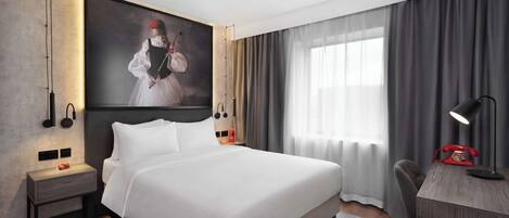 A modern hotel room with a large bed, bedside tables, a desk, and a chair.