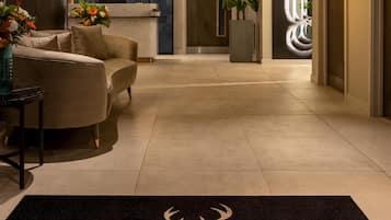 A hotel lobby with a reception desk, seating area, and a carpet with the hotel name.