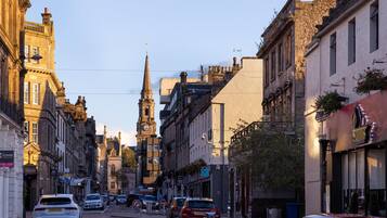 Una calle histórica con una destacada torre de iglesia, edificios antiguos y coches aparcados.