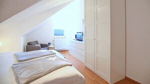 Ein Schlafzimmer mit Bett, Schreibtisch, Stuhl und Kleiderschrank.