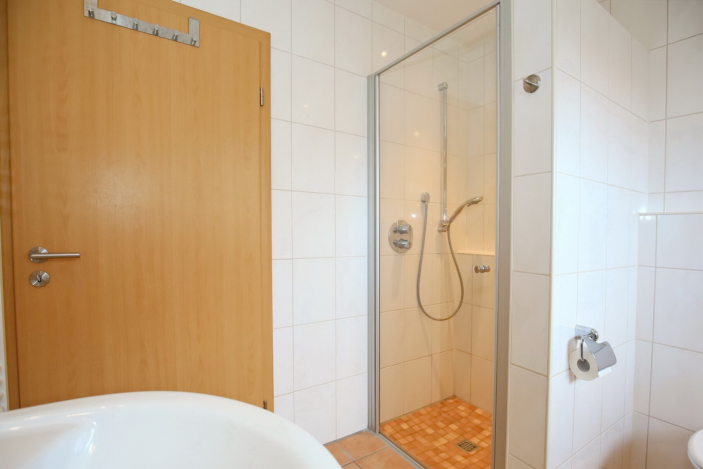 Un baño con cabina de ducha de vidrio, puerta de madera y bañera blanca.