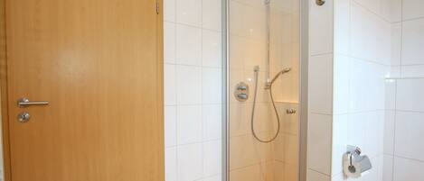 Un baño con cabina de ducha de vidrio, puerta de madera y bañera blanca.