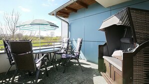 Un espace extérieur aménagé avec du mobilier de jardin, notamment des chaises et une table, ainsi qu’un barbecue.