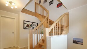 Una escalera de madera con un muro blanco y un cuadro enmarcado.
