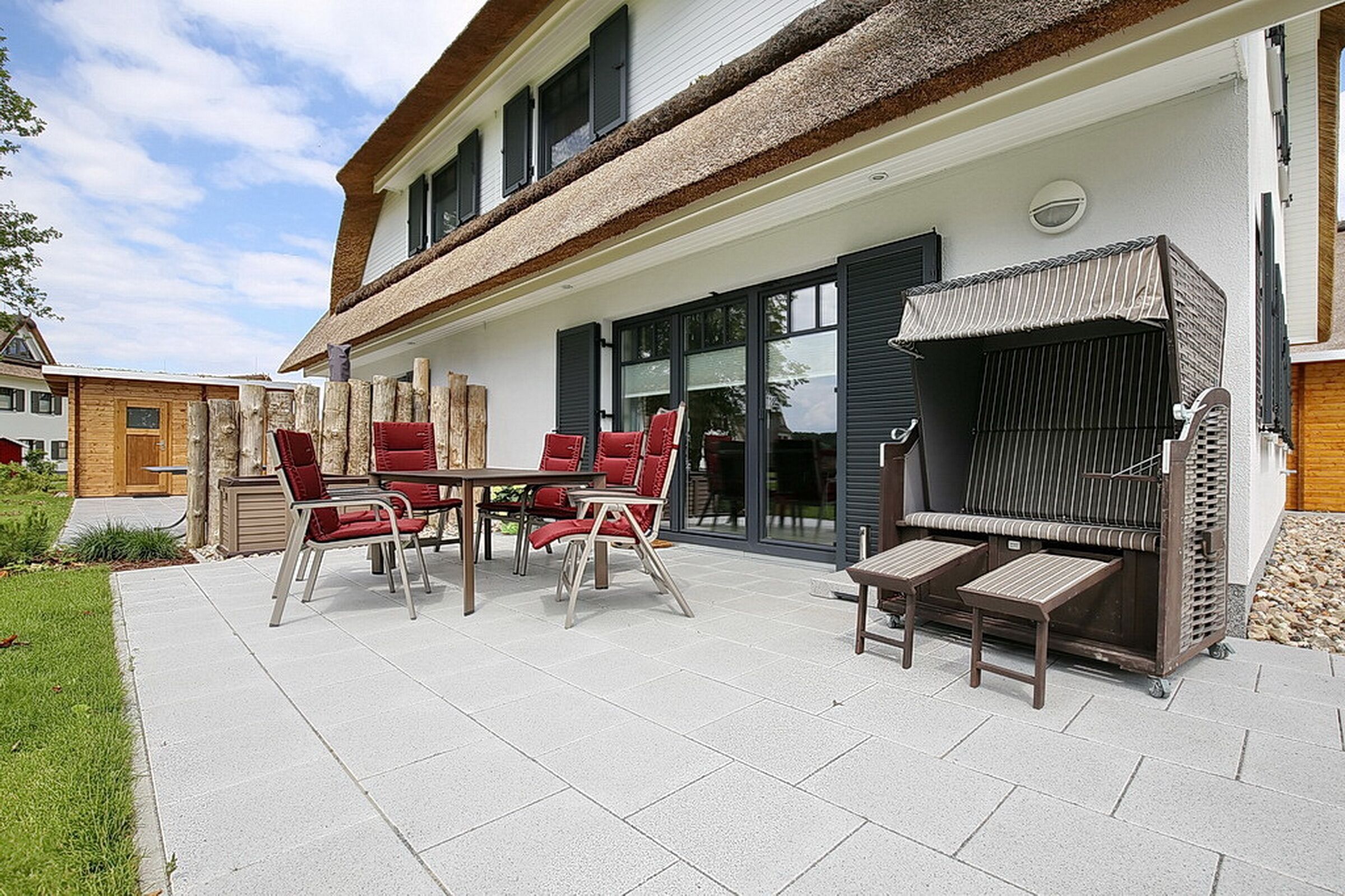 An outdoor patio with a dining table and chairs, a barbecue grill, and a covered seating area.