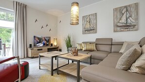 Una sala moderna con sofá, mesa de centro, televisor y obras de arte.