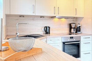 A modern kitchen with wooden cabinets, stainless steel appliances, and a wooden countertop.