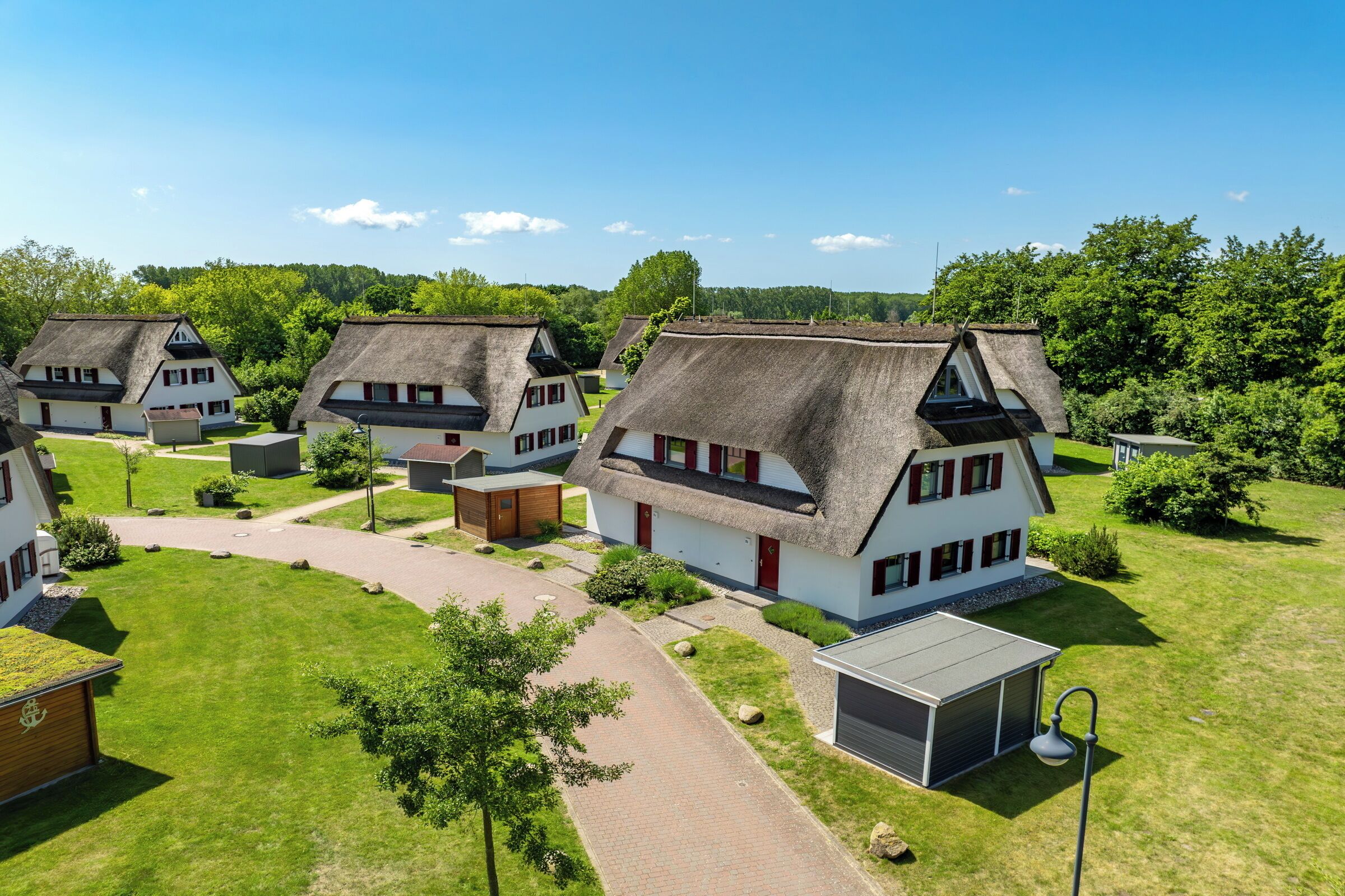 Een rij traditionele huizen met rieten daken, gerangschikt in een rij met een geplaveid pad ertussen.