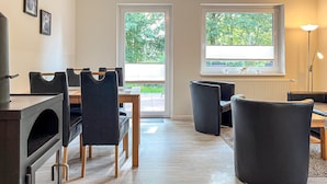 Een moderne woonkamer met een eethoek, grote ramen en een open haard.