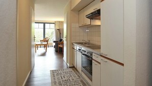 Eine moderne Küche mit weißen Schränken, einem Einbauofen und einem Fenster mit Vorhängen.