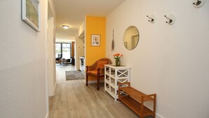 A hallway with a wooden bench, a white console table with a vase of flowers, and a chair. - Papillon Wohnung 02-3 (Ostseebad Boltenhagen)