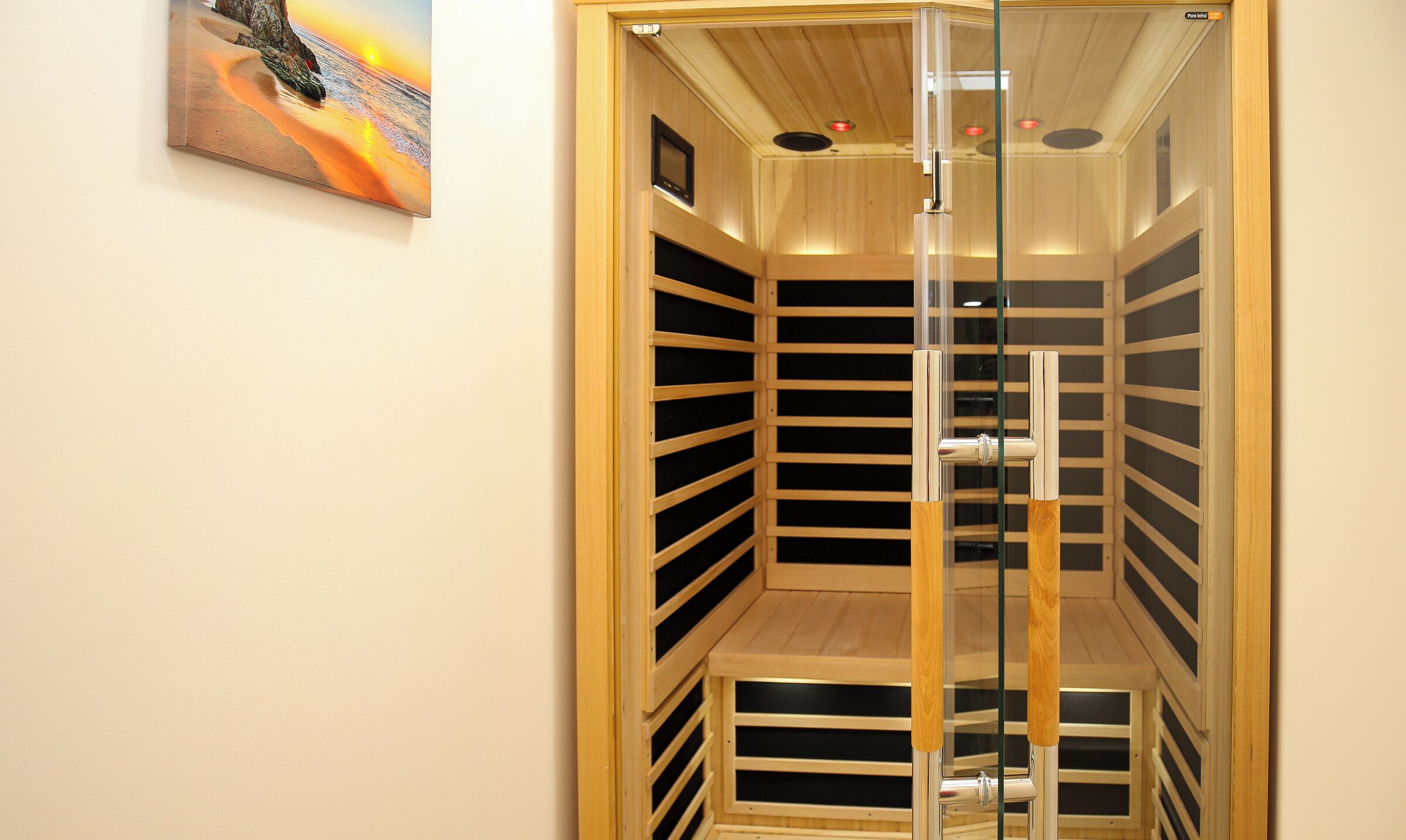 Un sauna avec un intérieur en bois, une porte en verre et un téléviseur fixé au mur.