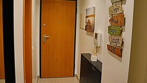 A hallway with a wooden door, a black cabinet, and a wall with motivational signs. - 1 bedroom apartment 200 meters from the beach (MONTE GORDO)