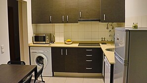 A compact kitchen with dark cabinets, a microwave, a washing machine, and a refrigerator. - 1 bedroom apartment 200 meters from the beach (MONTE GORDO)