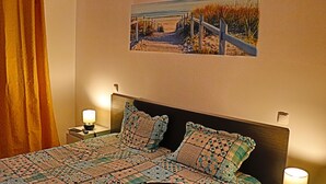 A bedroom with a bed, two bedside lamps, a nightstand, a picture on the wall, and a curtain. - 1 bedroom apartment 200 meters from the beach (MONTE GORDO)