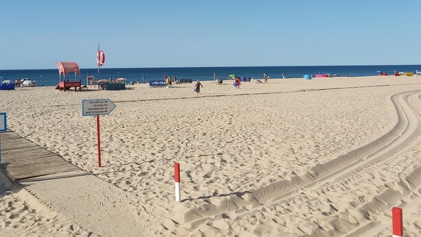 A sandy beach with a clear blue sky. There are footprints and tire tracks in the sand. - 1 bedroom apartment 200 meters from the beach (MONTE GORDO)