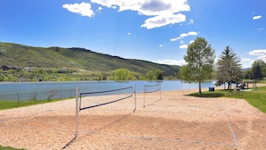 A beach volleyball court with net, sand, and a lake view. - Spacious Avon Retreat | Pool, Tennis, 2 Masters & Free Shuttle (Avon)